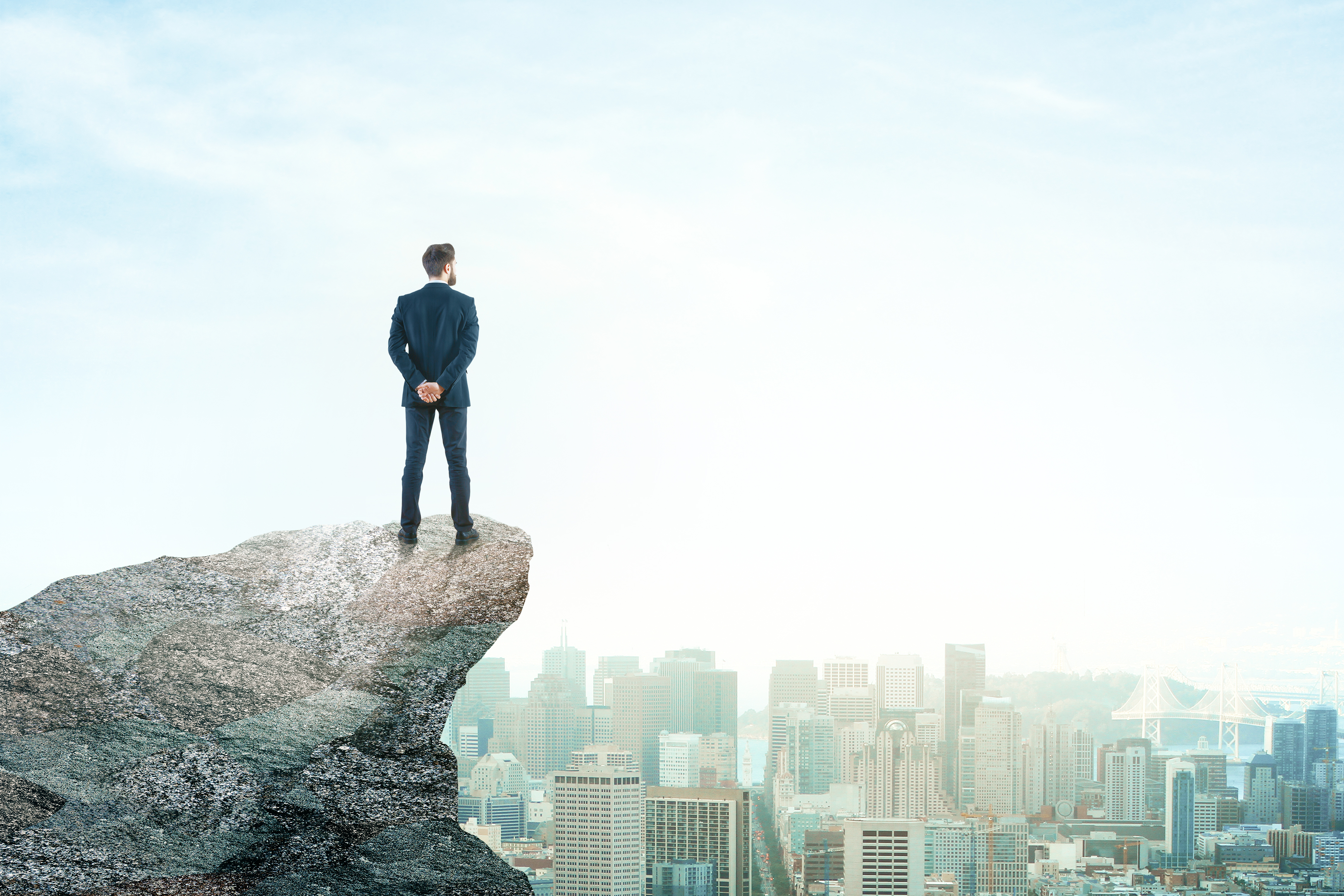 man on cliff look down at city